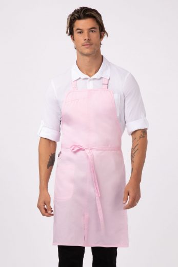 A man with tattoos wearing Chef Works’ Brio Bib Apron in pink as part of Chef Works culinary uniform pieces